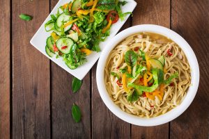 Top View of Noodle Bowl Next to Salad on Wood Background | Vitacost Blog