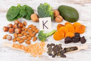 Assorted Vitamin K Foods Such as Spinach, Almonds & Apricots Arranged on Distressed White Wood Surface | Vitacost.com.blog