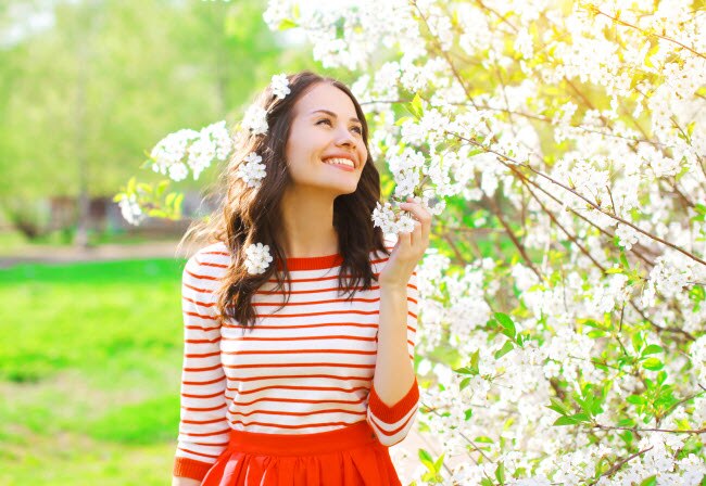 Cheerful Woman in Red and White Dress Following Tips to Reduce Symptoms of Allergies and Asthma Smelling Spring Flowers | Vitacost.com/blog