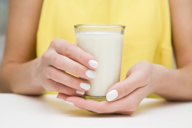 Woman in Yellow Dress Holding Glass of Milk She's Drinking to Combat Nutrient Deficiencies | Vitacost.com/blog