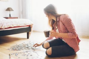 Woman Concerned About Brain Health Trying to Activate Neuroplasticity by Working on Jigsaw Puzzle on Bedroom Floor | Vitacost.com/blog