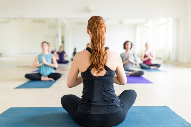 Back View of  Pony-Tailed Women Teaching Yoga Class to Demonstrate the Power of Women Leading Women | Vitacost.com/blog