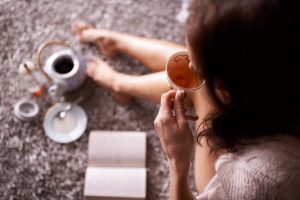 Overhead View of Woman Sipping Tea While Sitting on Floor Read Book as Example of Mindfulness Techniques | Vitacost.com/blog