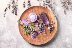 Lavender Essential Oil Uses Demonstrated by Bottle of Oil, Candle and Fresh Buds on Circular Wooden Cutting Board | Vitacost.com/blog