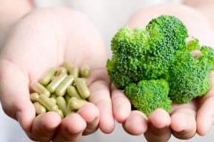 Two Open Hands Holding Different Types of Vitamins in Capsules and Broccoli Florets | Vitacost.com/blog