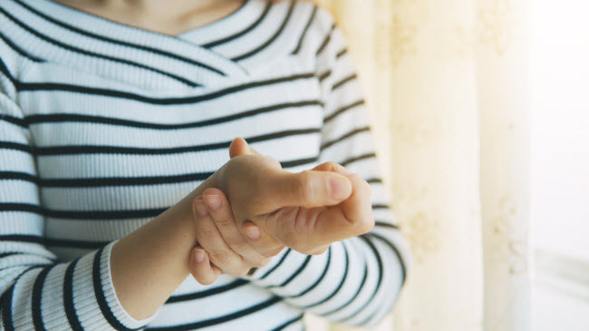 Torso View of Woman Holding Wrist in Pain Wondering About the Signs and Symptoms of Arthritis | Vitacost.com/blog