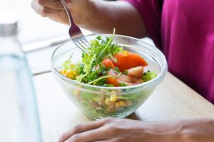 Example of Healthy Salads in Glass Bowl With Assorted Veggies Being Enjoyed by Woman in Magenta Shirt | Vitacost.com/blog