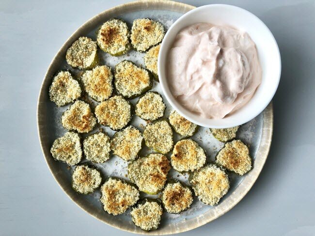 Oven-baked pickles on a plate with spicy dipping sauce