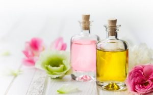 Two Bottles of Face Oil With Benefits for Skin Surrounded by Flowers on White Wooden Surface | Vitacost.com/blog