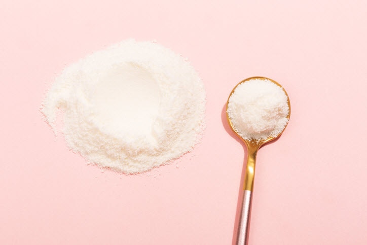 Collagen peptide powder on pink background