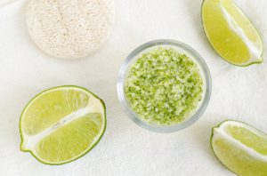Overhead View of DIY Salt Scrub Made with Lime Essential Oil on White Towel Background with Sponge | Vitacost.com/blog