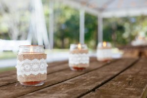 Homemade Citronella Candles in Jars Placed on Wooden Patio Table Under White Tent | Vitacost.com/blog