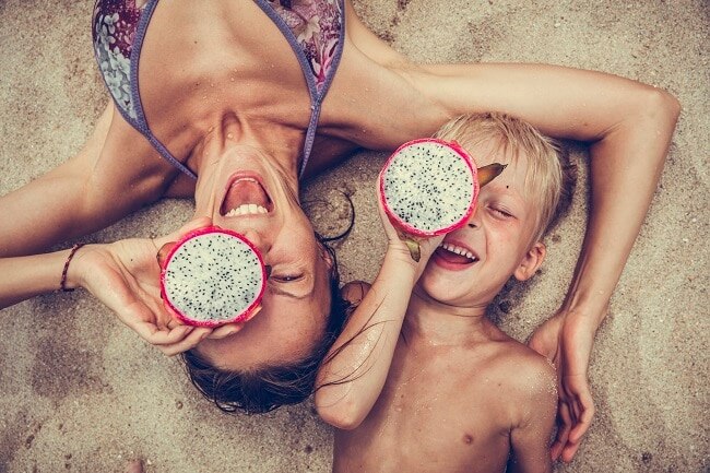 Raw Food Diet Fruits in Season this Summer Mother and Son Eating Raw Dragon Fruit on the Beach in Summer | Vitacost.com/Blog