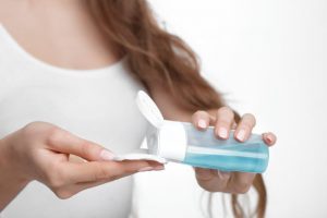 Torso View of Woman Discovering How to Use Micellar Water Pouring Blue Liquid onto Cotton Pad | Vitacost.com/blog