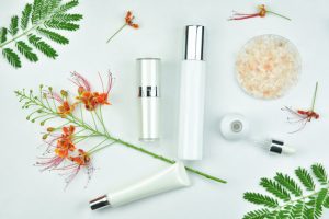 Assortment of Best Natural Skincare Products for Aging Skin on White Surface Surrounded by Botanicals