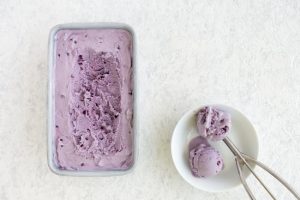 How to Make Dairy Free Ice Cream Represented by Blueberry Ice Cream Being Scooped From Tin on White Countertop | Vitacost.com/blog