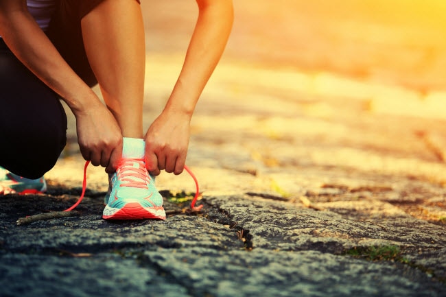 What's the Best Time of Day to Work Out? A Trainer Answers.  Woman Taking Advantage of Sunrise Hours as Best Time of Day to Work Out Tying Shoe on Pavement | Vitacost.com/blog