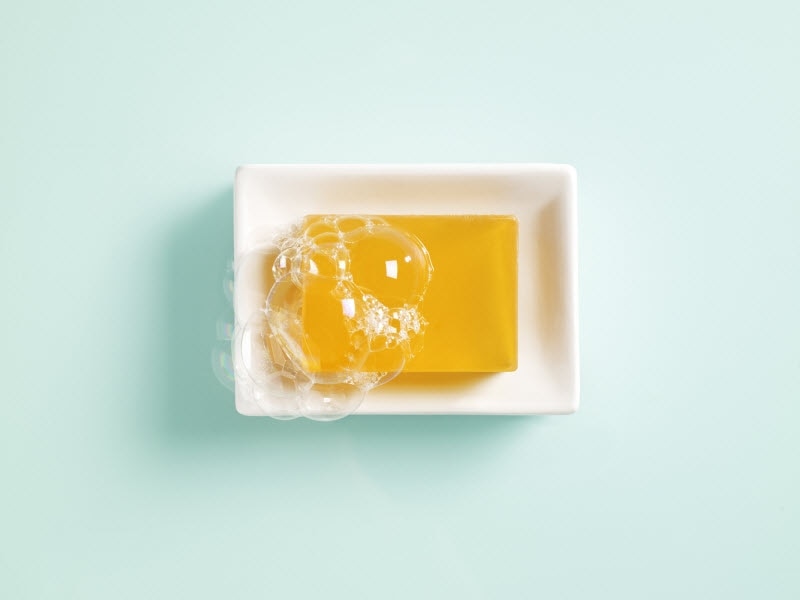 Bar of Orange Soap with Suds in White Soap Dish on Aqua Blue Surface to Represent Best Products for Adult Acne | Vitacost.com/blog