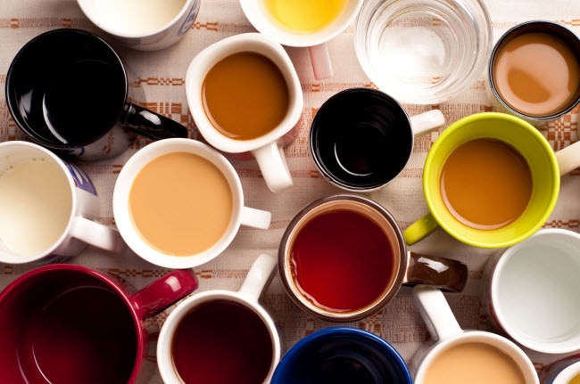 The Effects of Caffeine on the Brain Represented by Various Colored Mugs Filled with Coffee & Tea on Wooden Table | Vitacost.com/blog
