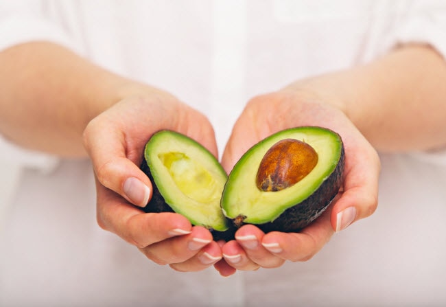 Healthy Keto Swaps to Keep You on Track Close-up View of Hands Holding Sliced-Open Avocado to Represent Healthy Keto Food Option | Vitacost.com/blog