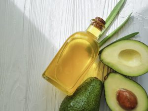 Sliced-Open Avocado With Avocado Oil on White Table to Represent the Benefits of Unsaturated Fat in the Diet | Vitacost.com/blog