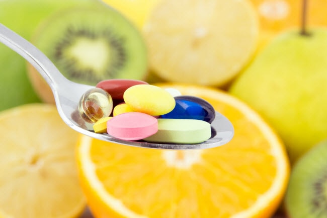 Metal Spoon With Assorted Color Vitamin Supplements With Colorful Citrus Fruit to Represent Why You Should Take Vitamins With Food | Vitacost.com/blog