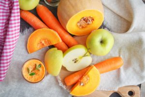 Assortment of Apples, Squash and Carrots on Cutting Board With Pink-White Checked Napkin to Represent Essential Nutrients for the Autumn Season | Vitacost.com/blog