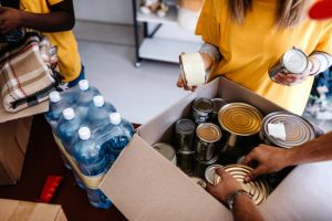 Volunteers Packing Canned Goods & Water into Boxes for Food Bank Donation as Example of How to Build Empathy | Vitacost.com/blog