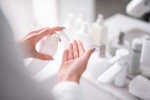 Hands-Only View of Woman Learning What to Do for Eczema Squeezing Lotion from White Bottle into Palm of Hand | Vitacost.com/blog