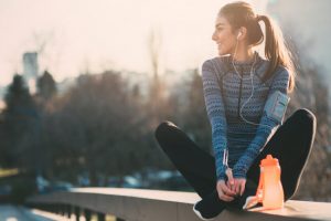Woman Following Vegan Nutrition Tips to Support Bone Health Exercising Outdoors While Listening to Music on Headphones | Vitacost.com/blog