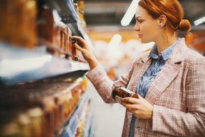 Side View of Red-Headed Woman Concerned About Greenwashing Reading Product Labels While Shopping | Vitacost.com/blog