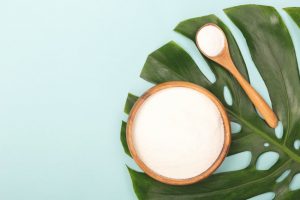 What is Inulin Represented by Wooden Bowl & Spoon Filled with White Powder on Large Decorative Green Leaf | Vitacost.com/blog