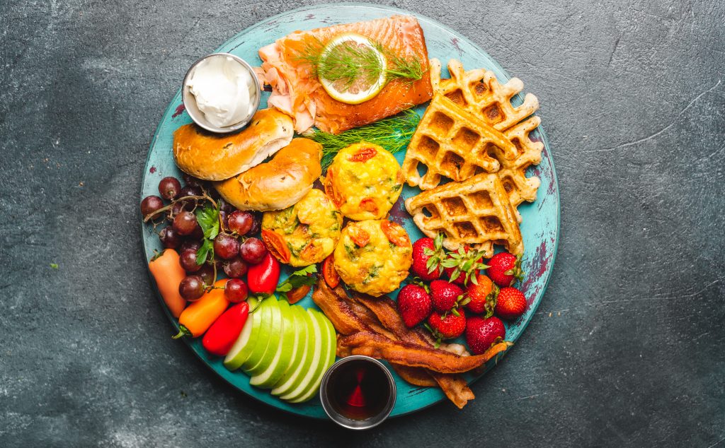 Brunch board with salmon, waffles, fruit, bacon and bagel