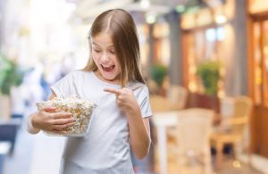 Girl with Celiac Disease Happily Pointing at Bowl of Popcorn Because it's a Great Gluten-Free Snack for Kids | Vitacost.com/blog