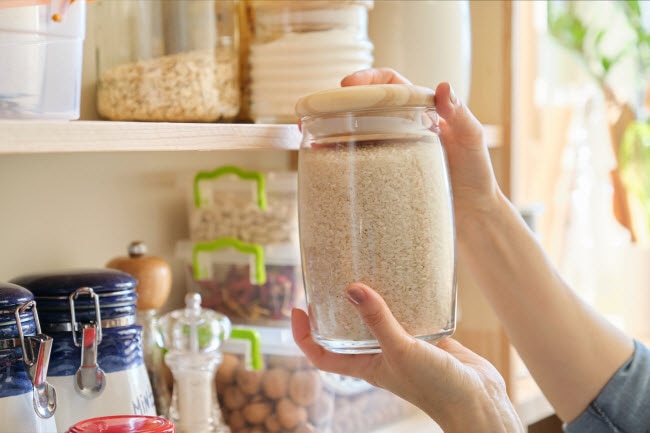 Woman Holding Jar Fill of Rice in Pantry With Other Smart Food Waste Solutions as Part of Strategy to Reduce Food Waste | Vitacost.com/blog