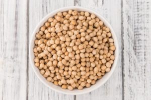 Concept of How to Eat Chickpeas Represent by Overhead View of White Bowl Filled with Chickpeas on White Wooden Surface | Vitacost Blog