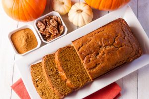 Overhead View of Sliced Loaf of Pumpkin Bread Surrounded by Autumn Accents Such as Pumpkins and Cinnamon to Represent Vitacost Fall Products | Vitacost.com/blog