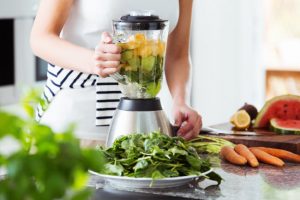 Torso View of Woman in Modern Kitchen Setting Blending Fresh Produce in Blender to Reap Low-Fat Diet Benefits | Vitacost.com/blog