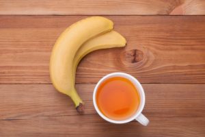 What is Banana Peel Tea Represented by Two Bananas and Cup of Orange-Colored Tea on a Wooden Table | Vitacost.com/blog