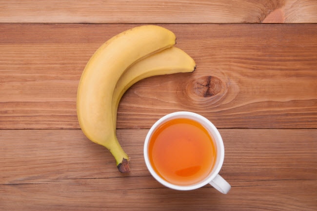What is Banana Peel Tea Represented by Two Bananas and Cup of Orange-Colored Tea on a Wooden Table | Vitacost.com/blog