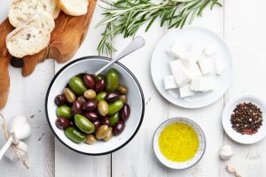 Overhead View of Bowls Filled with Olives, Oil, Cheese and Spices with Bread on Cutting Board to Represent What is the MedDairy Diet | Vitacost.com.blog