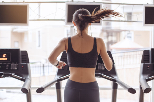 Back View of Woman With Pony Tail and Black Workout Clothing Running on Treadmill After She Learned How to Choose a Gym | Vitacost.com/blog