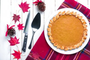 Pumpkin Pie with Red Leaves & Pinecones on Plaid Placemat on White Wood Surface to Represent Healthy Holiday Desserts | Vitacost.com/blog