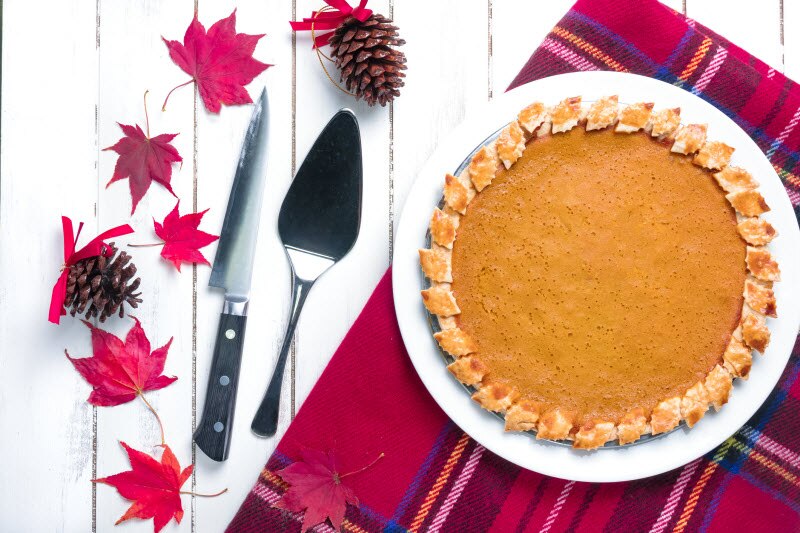 Pumpkin Pie with Red Leaves & Pinecones on Plaid Placemat on White Wood Surface to Represent Healthy Holiday Desserts | Vitacost.com/blog