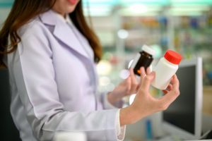 Torso View of Woman Shopping for Supplements Holding Two Bottles and Wondering if Expensive Vitamins are Better Than Cheap Ones | Vitacost.com/blog