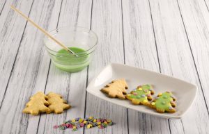 DIY Food Coloring in Bowl with Brush Beside White Plate With Christmas Tree Cookies | Vitacost.com/blog