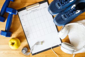 Exercise Gear Including Blue Weights, Measuring Tape, Blue Sneakers, Headphones & Clipboard to Represent Starting a New Fitness Routine | Vitacost.com/blog