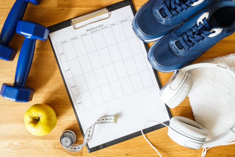 Exercise Gear Including Blue Weights, Measuring Tape, Blue Sneakers, Headphones & Clipboard to Represent Starting a New Fitness Routine | Vitacost.com/blog