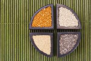 Wooden Sectioned Bowl with Colorful Ancient Grains on Green Bamboo Mat to Represent 2020 Predictions for Healthy Food Trends | Vitacost.com/blog