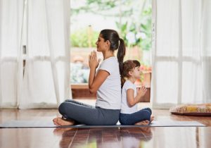 Woman Teaching Self Care Ideas to Daughter as They Meditate Together on Mat in Living Room | Vitacost.com/blog